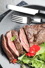 Photo of Delicious grilled beef meat served with greens on table, top view