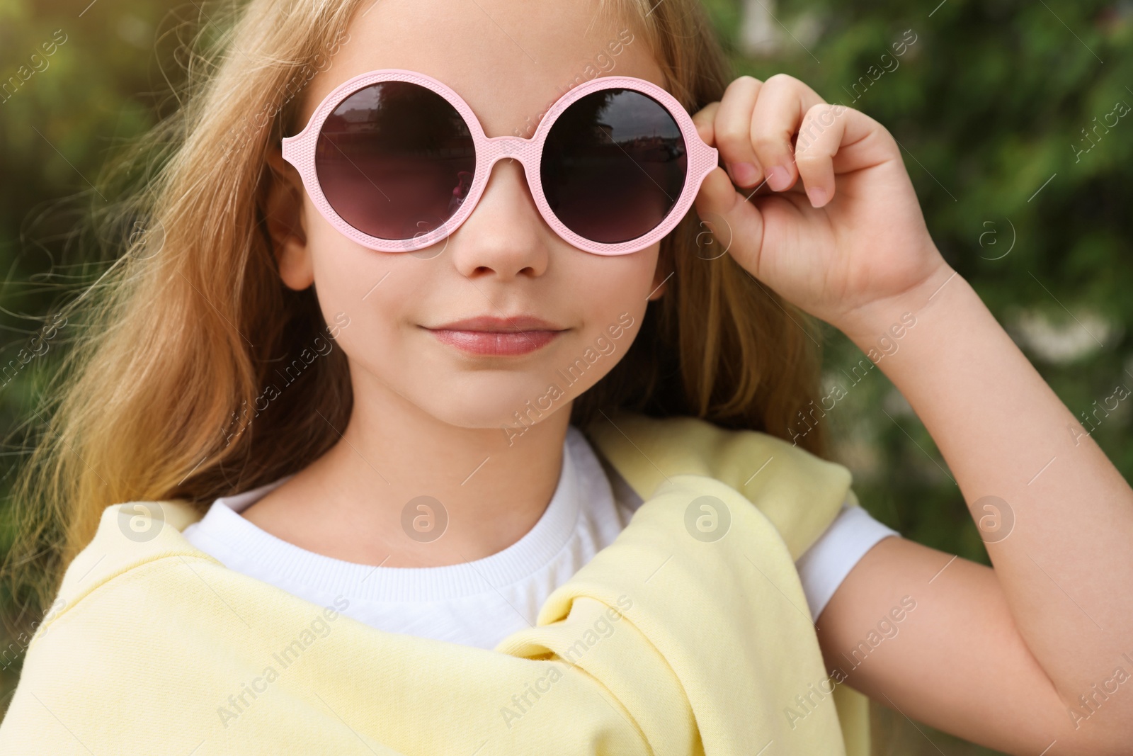 Photo of Girl in stylish sunglasses near spruce trees outdoors, closeup
