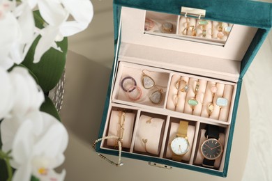 Photo of Elegant jewelry box with beautiful bijouterie and expensive wristwatches on beige table, top view