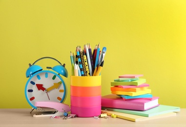 Photo of Set of school stationery and alarm clock on table against yellow background. Back to school
