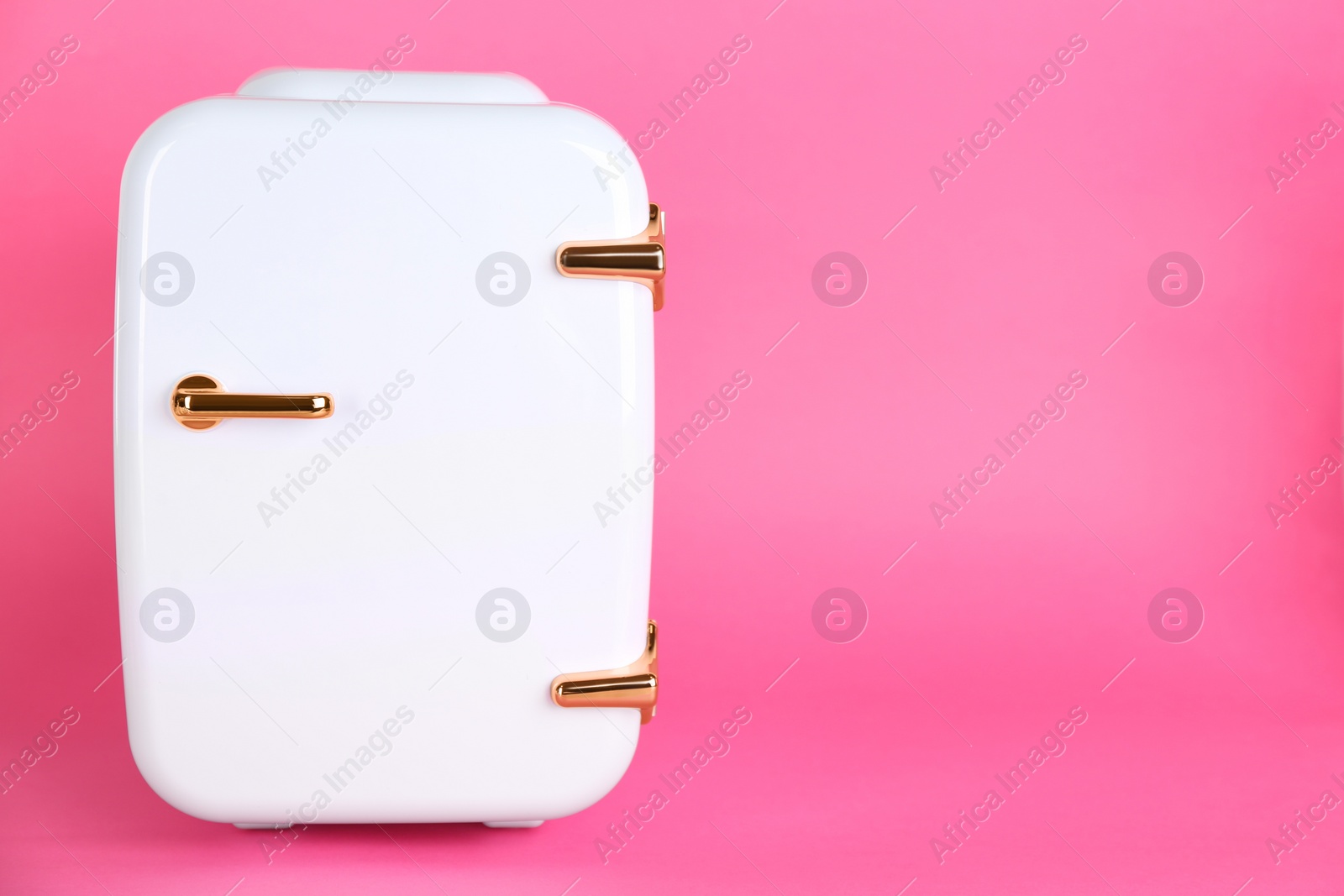 Photo of Cosmetic refrigerator on pink background, space for text