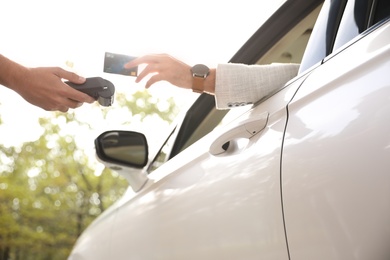 Man sitting in car and paying with credit card at gas station, closeup