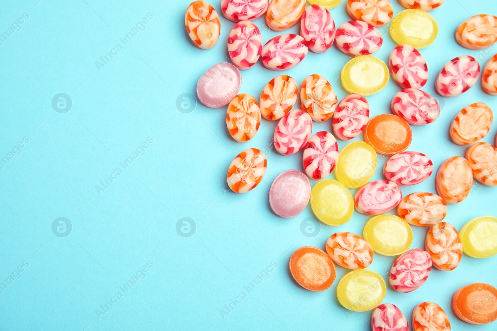 Photo of Flat lay composition with delicious colorful candies and space for text on color background