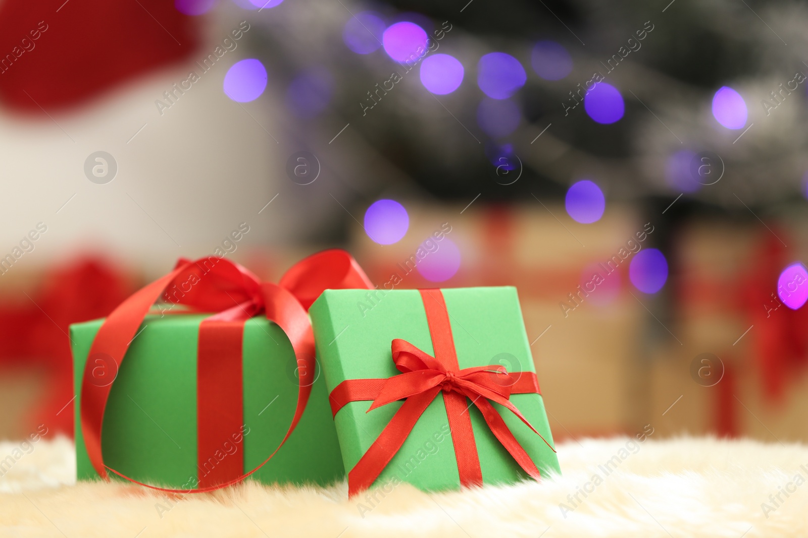 Photo of Christmas gifts on fuzzy rug against blurred background, space for text