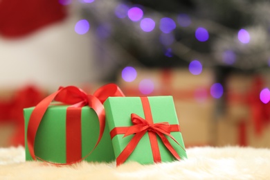 Photo of Christmas gifts on fuzzy rug against blurred background, space for text