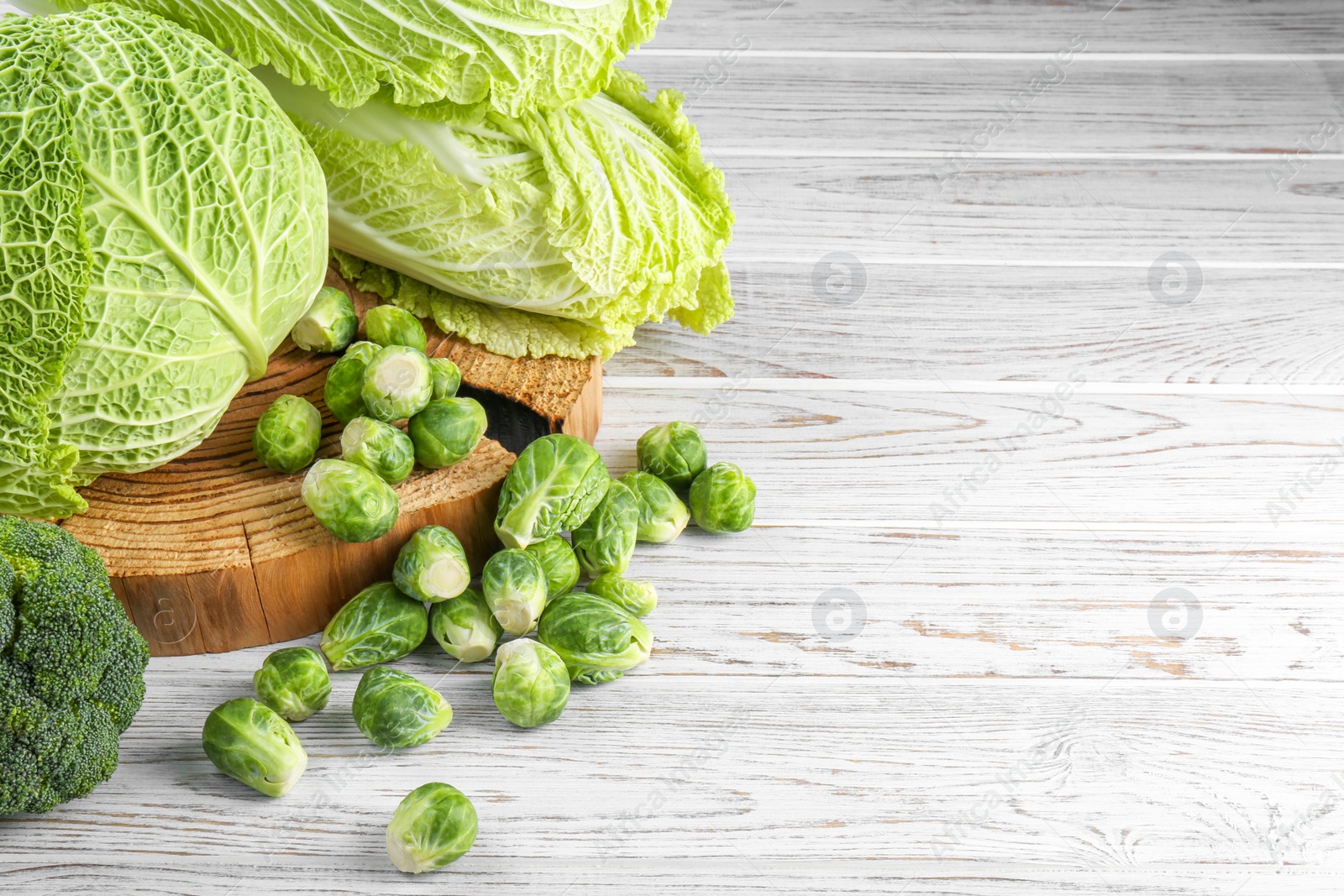 Photo of Different types of fresh cabbage on white wooden table, space for text