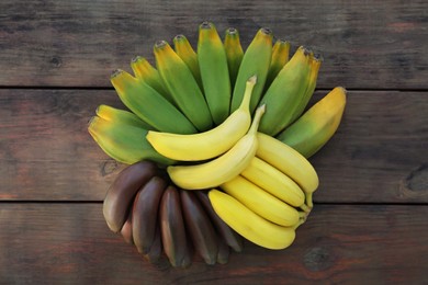 Photo of Different sorts of bananas on wooden table, flat lay