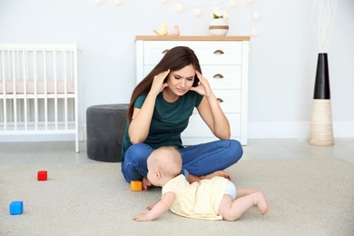 Young mother suffering from postnatal depression and cute baby girl at home