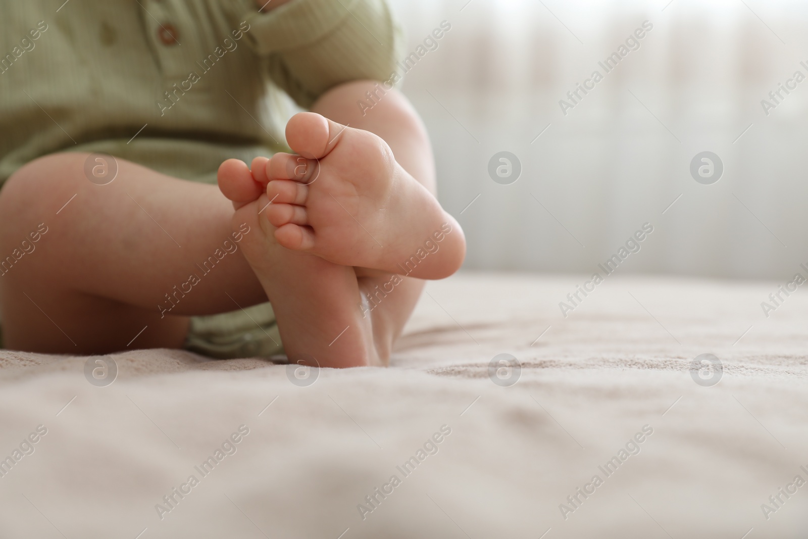 Photo of Baby sitting on bed at home, closeup. Space for text