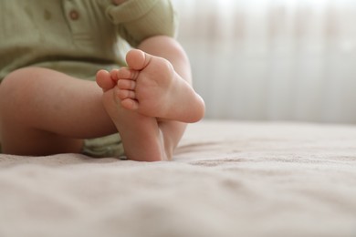 Photo of Baby sitting on bed at home, closeup. Space for text