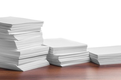 Photo of Stacks of paper sheets on wooden table against white background