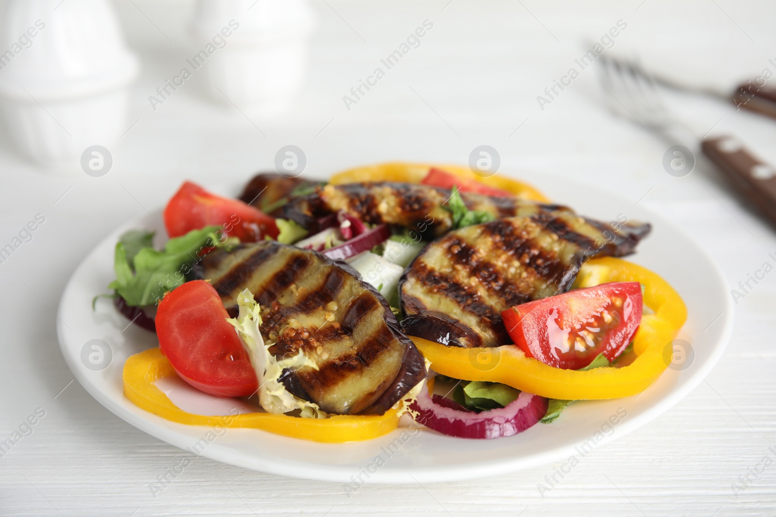 Photo of Delicious salad with roasted eggplant served on white wooden table, closeup