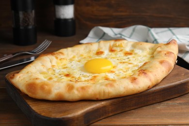 Fresh homemade khachapuri with cheese and egg on wooden table, closeup