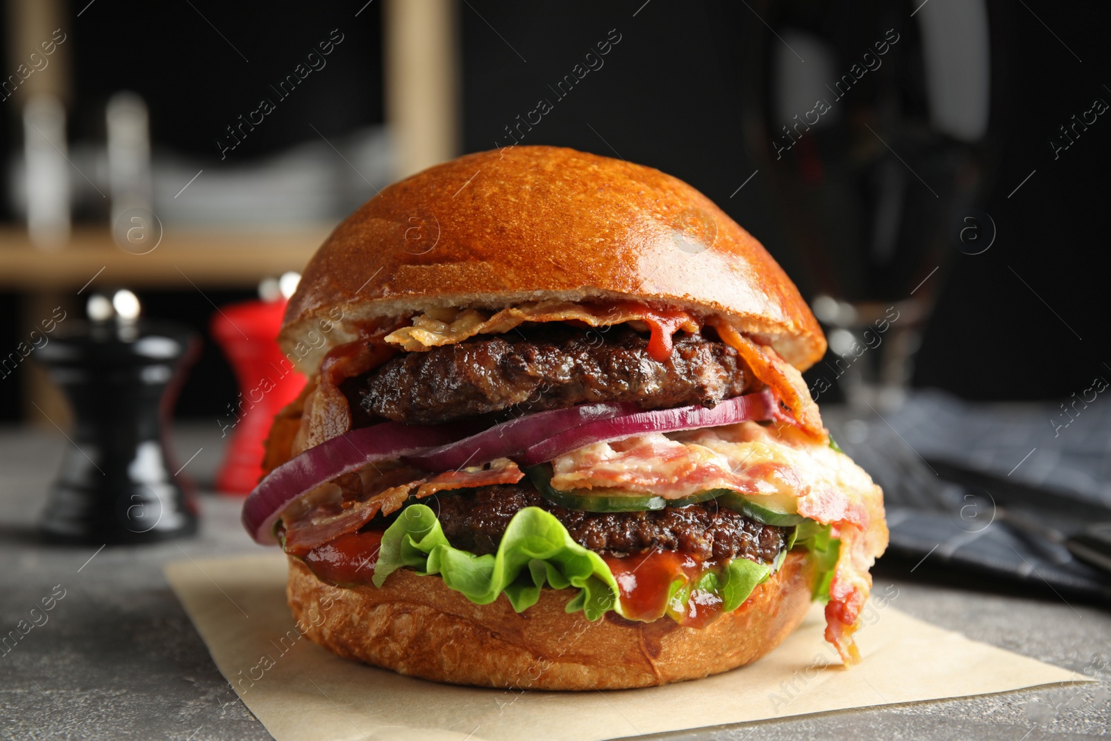 Photo of Tasty burger with bacon and lettuce on table