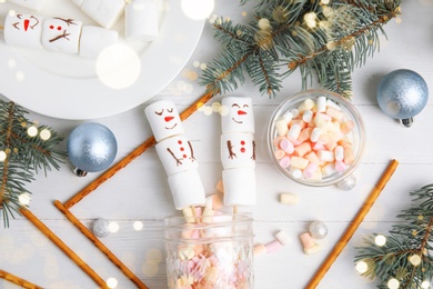 Image of Flat lay composition with funny snowmen made of marshmallows on white wooden table. Bokeh effect 