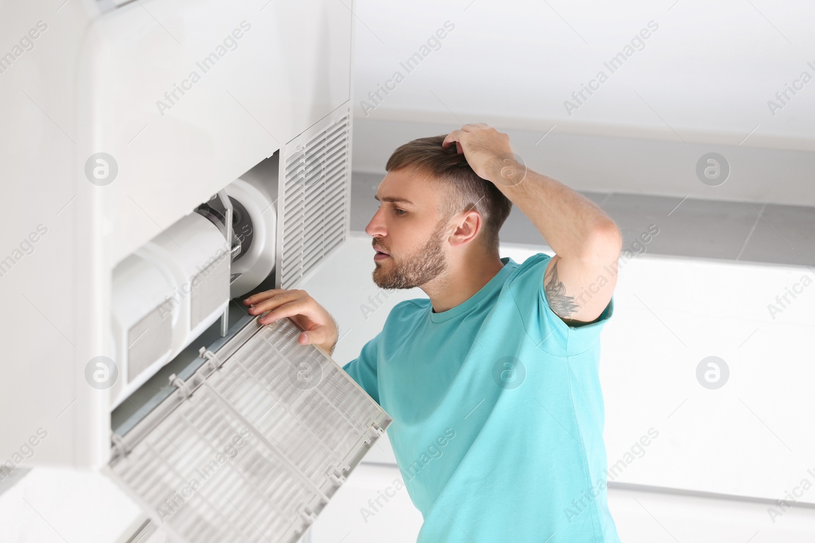 Photo of Young man fixing air conditioner at home