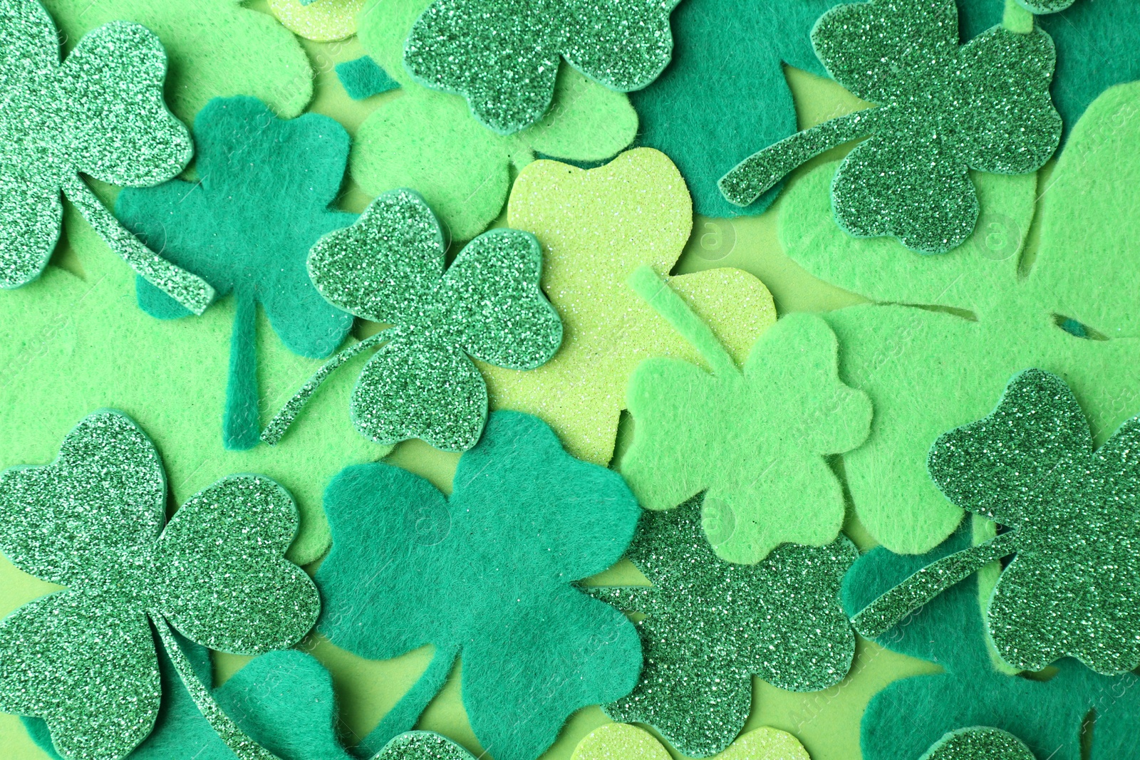 Photo of St. Patrick's day. Decorative clover leaves on green background, top view