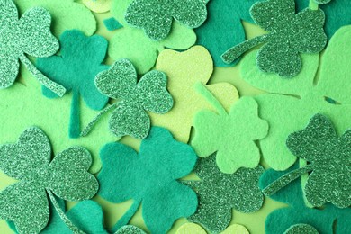 Photo of St. Patrick's day. Decorative clover leaves on green background, top view