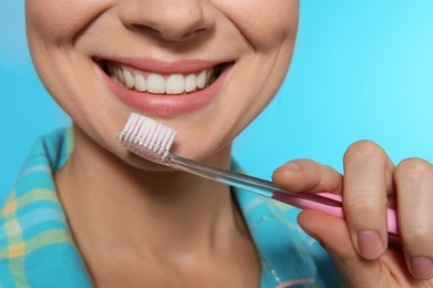 Woman with toothbrush on color background, closeup