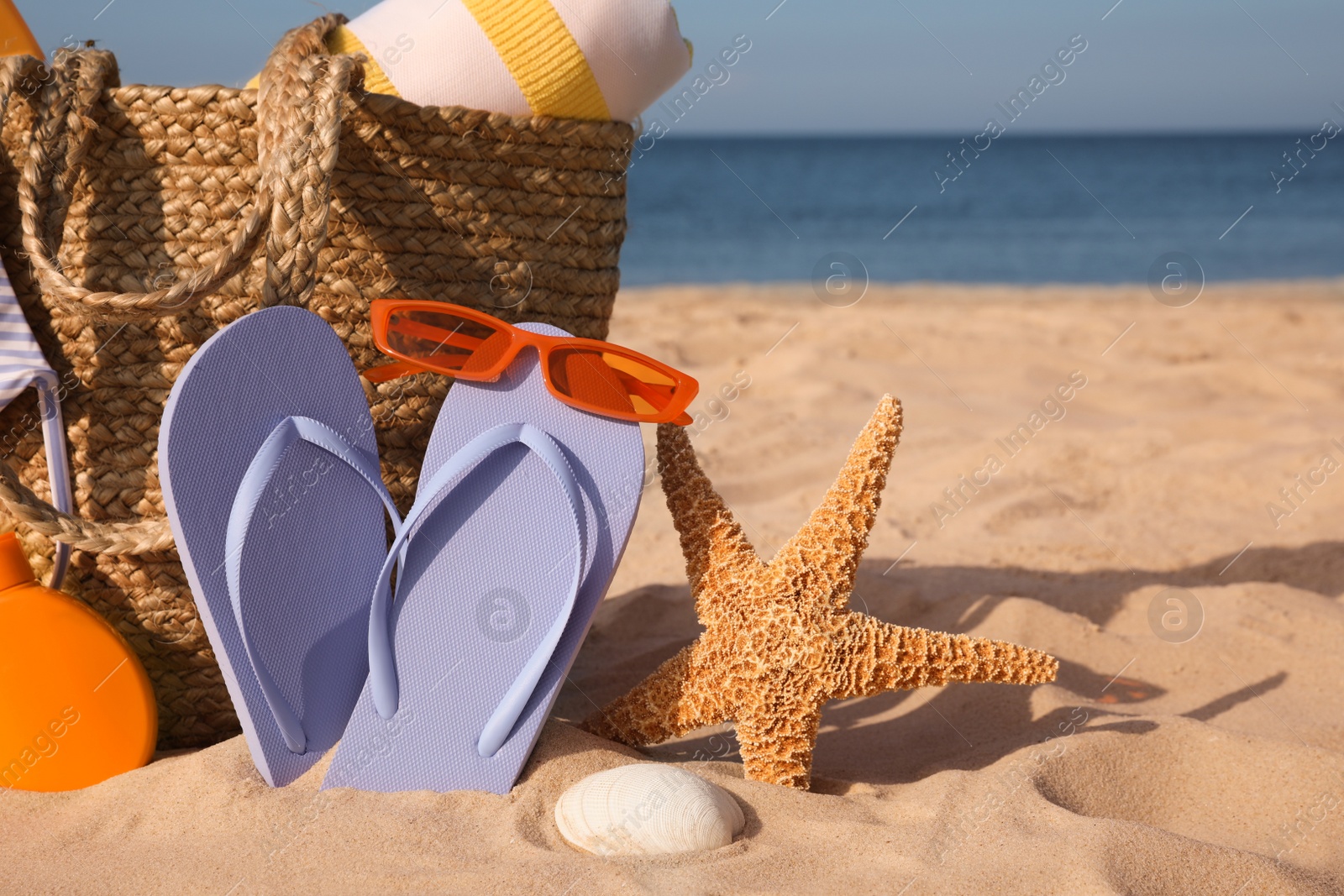 Photo of Bag and beach accessories on sand near sea