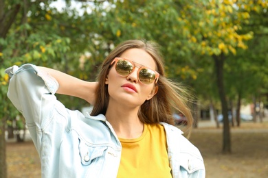 Photo of Young woman wearing stylish sunglasses in park