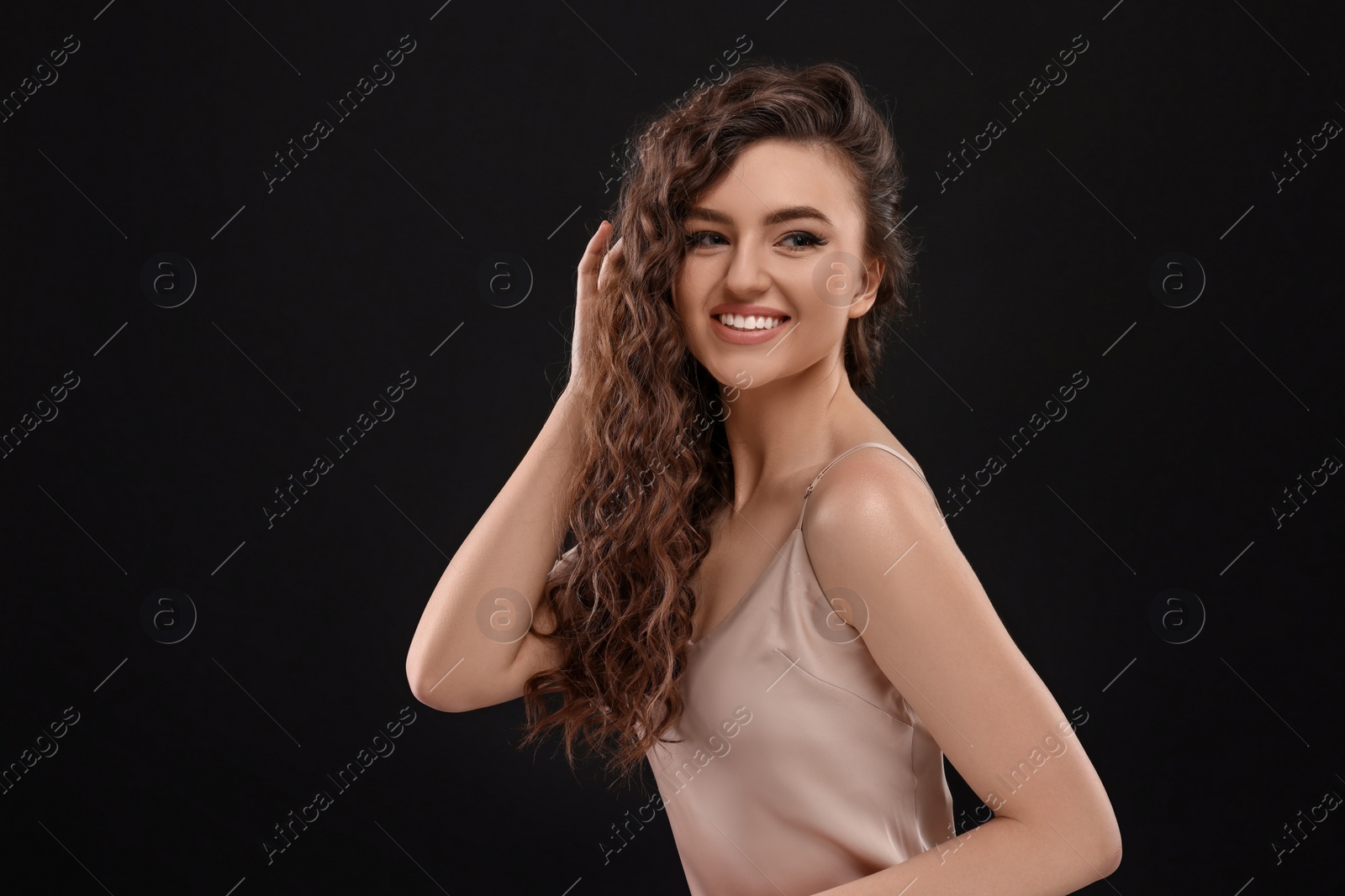 Photo of Beautiful young woman with long curly brown hair on black background, space for text