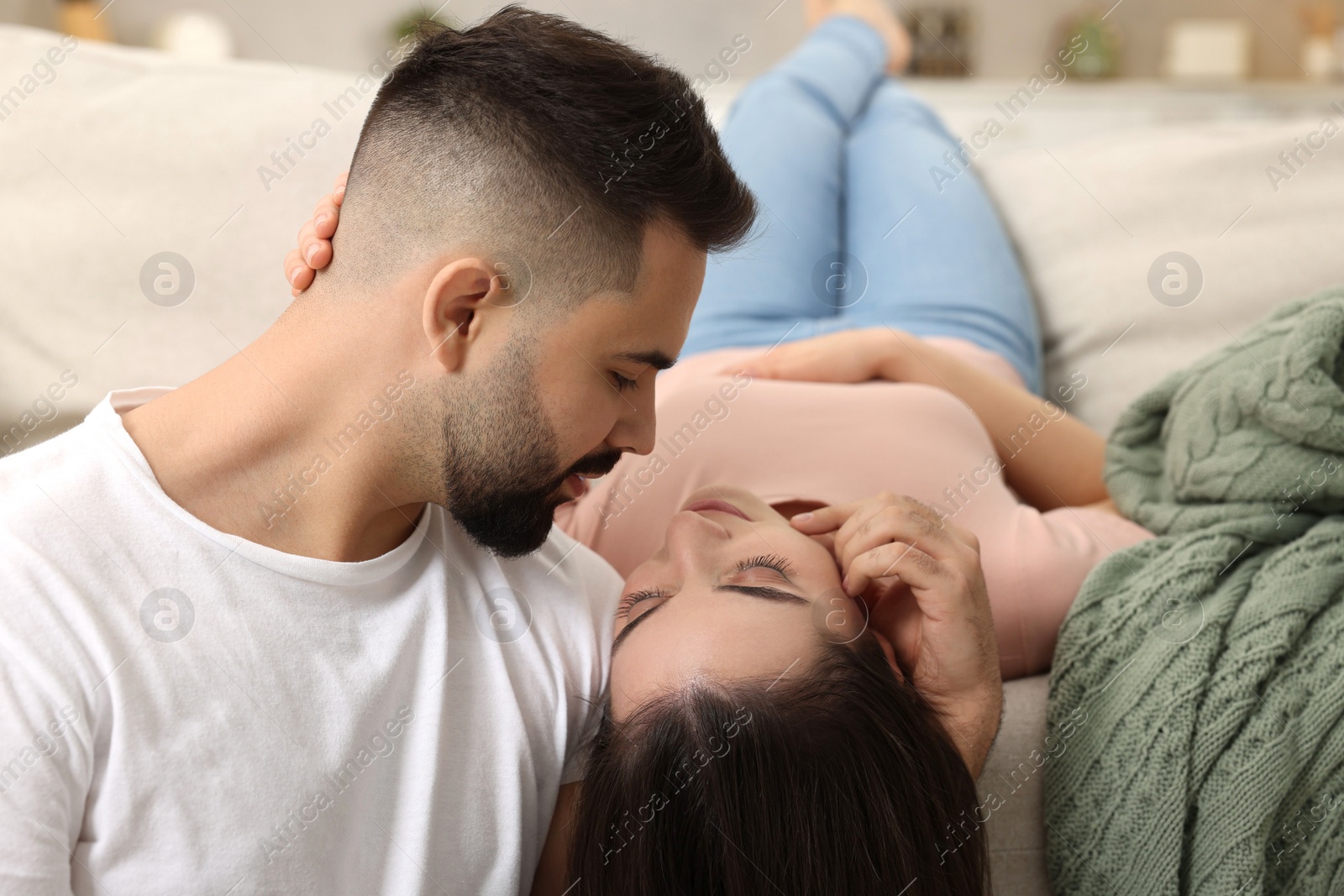 Photo of Affectionate young couple spending time together on sofa indoors