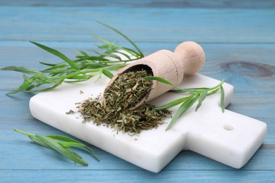 Photo of Dry and fresh tarragon on light blue wooden table