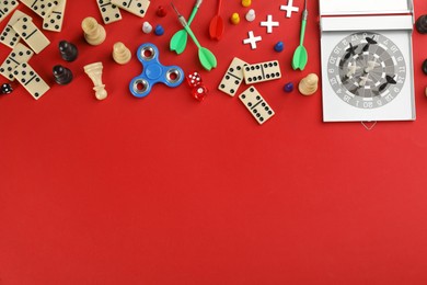 Photo of Different types of board games and its' components on red background, flat lay. Space for text