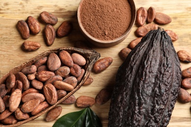 Photo of Cocoa pods with powder and beans on wooden table, flat lay