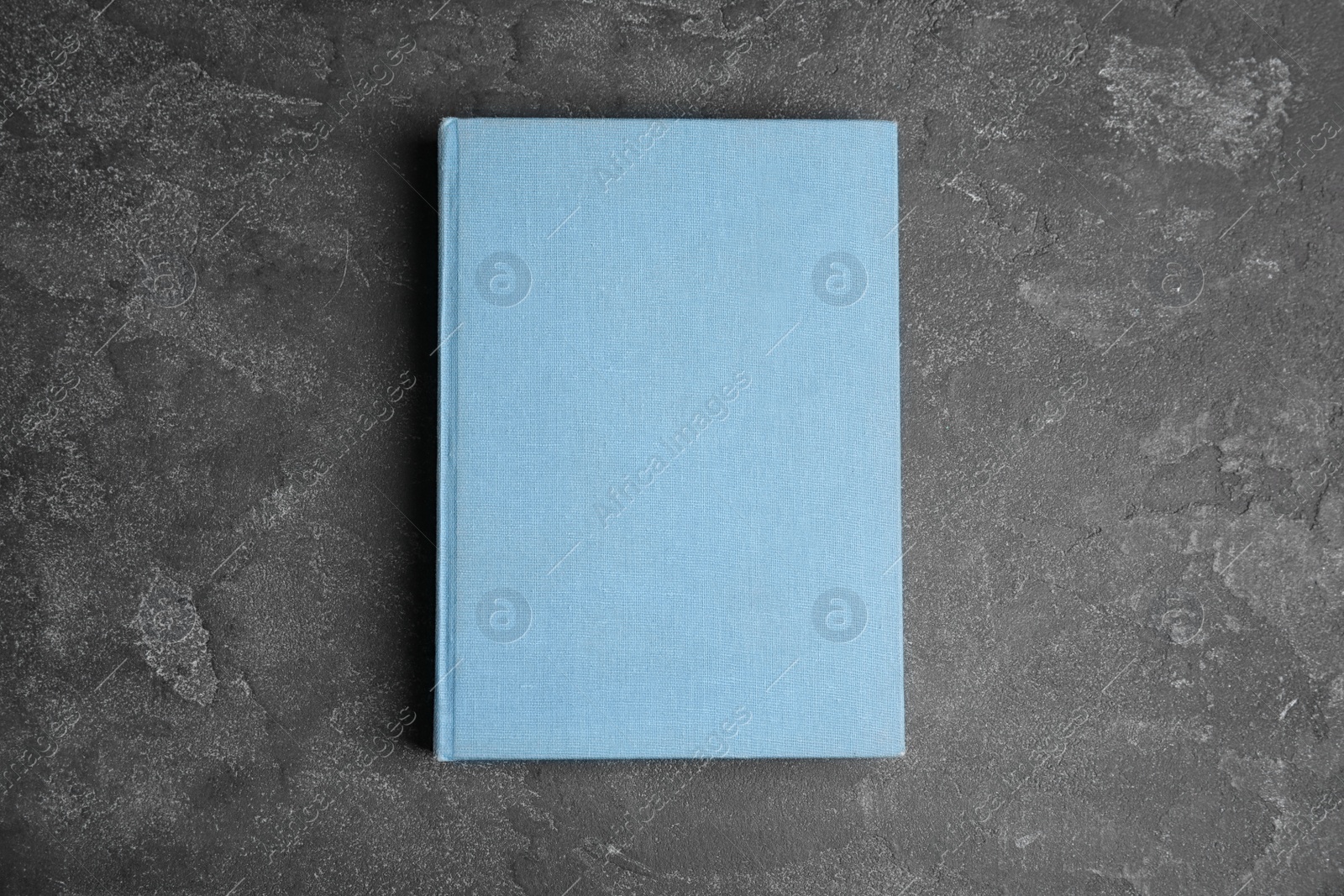 Photo of Hardcover book on grey stone table, top view. Space for text