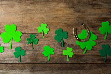 Flat lay composition with clover leaves and horseshoe on wooden background. St. Patrick's day