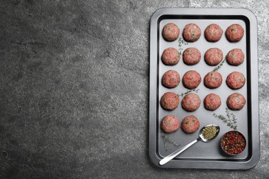 Many fresh raw meatballs on grey table, top view. Space for text