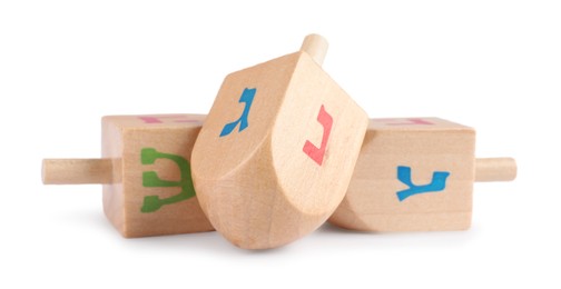 Photo of Hanukkah celebration. Wooden dreidels with jewish letters isolated on white