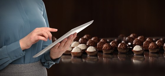 Image of Production line of chocolate candies. Woman working with tablet, closeup. Banner design