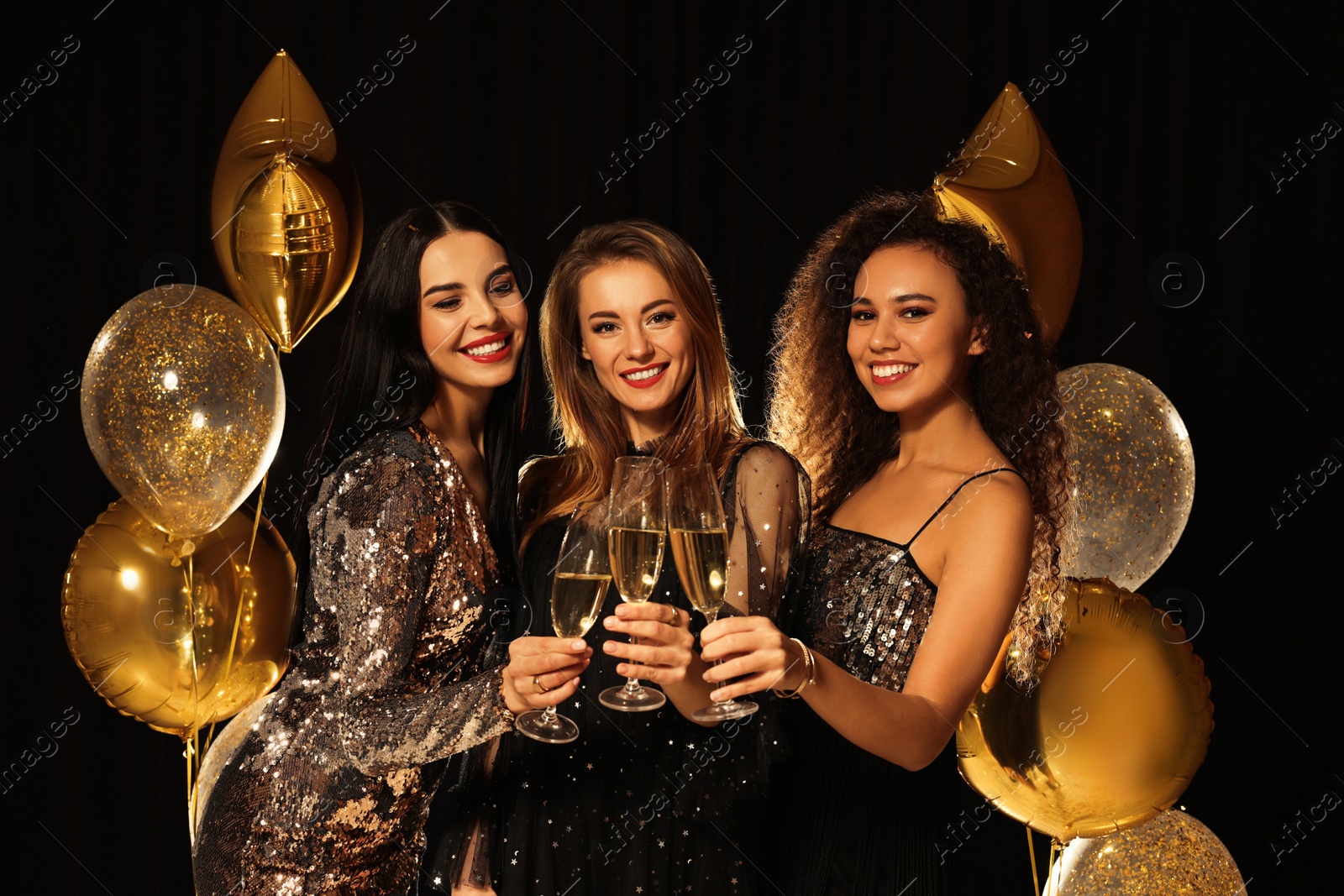 Photo of Happy women with glasses of sparkling wine celebrating New Year on black background