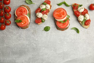 Photo of Delicious sandwiches with mozzarella, fresh tomatoes and basil on light grey table, flat lay. Space for text