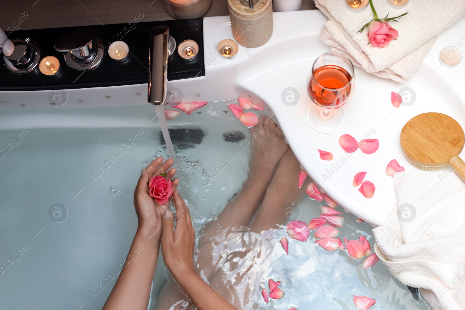 Photo of Woman holding rose flower while taking bath, above view. Romantic atmosphere