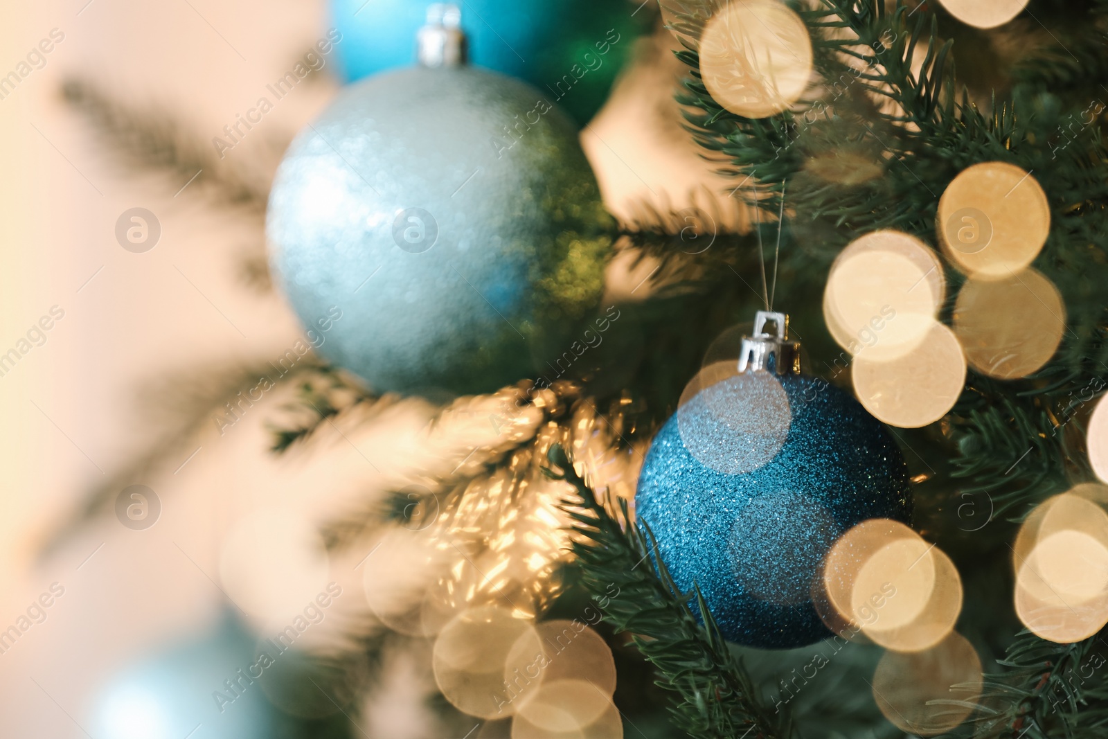 Photo of Christmas tree decorated with light blue festive balls on blurred background, closeup