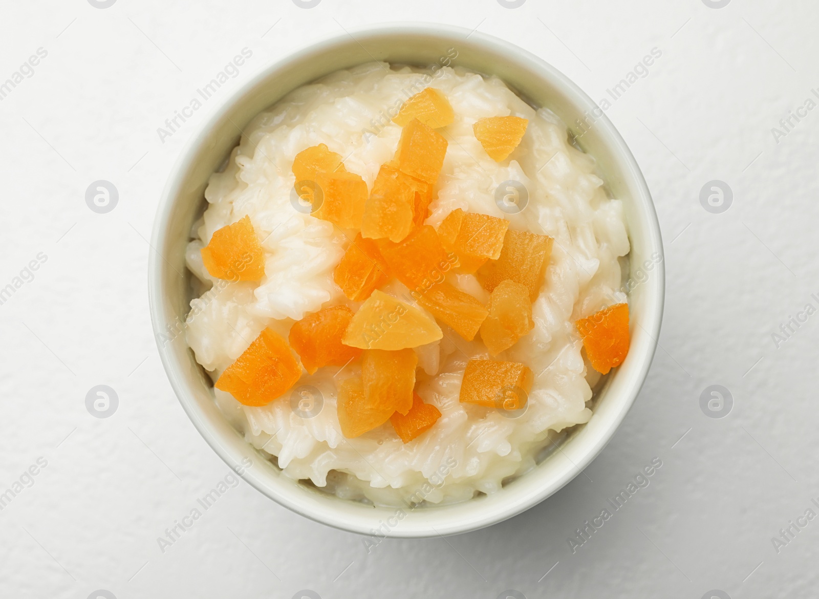 Photo of Delicious rice pudding with dried apricots on white table, top view