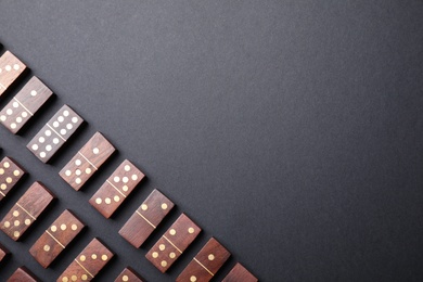 Wooden domino tiles on black background, flat lay. Space for text