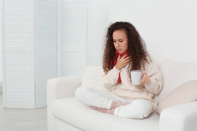 Photo of Sick African American woman with cup of hot drink at home