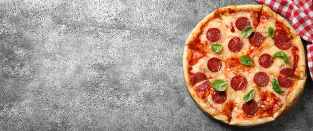 Top view of hot delicious pizza on grey table, space for text. Banner design 