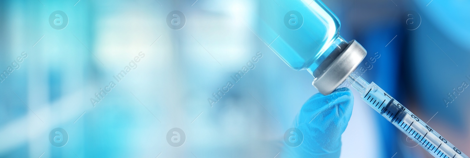 Image of Doctor filling syringe with medication from glass vial on blurred background, closeup. Banner design