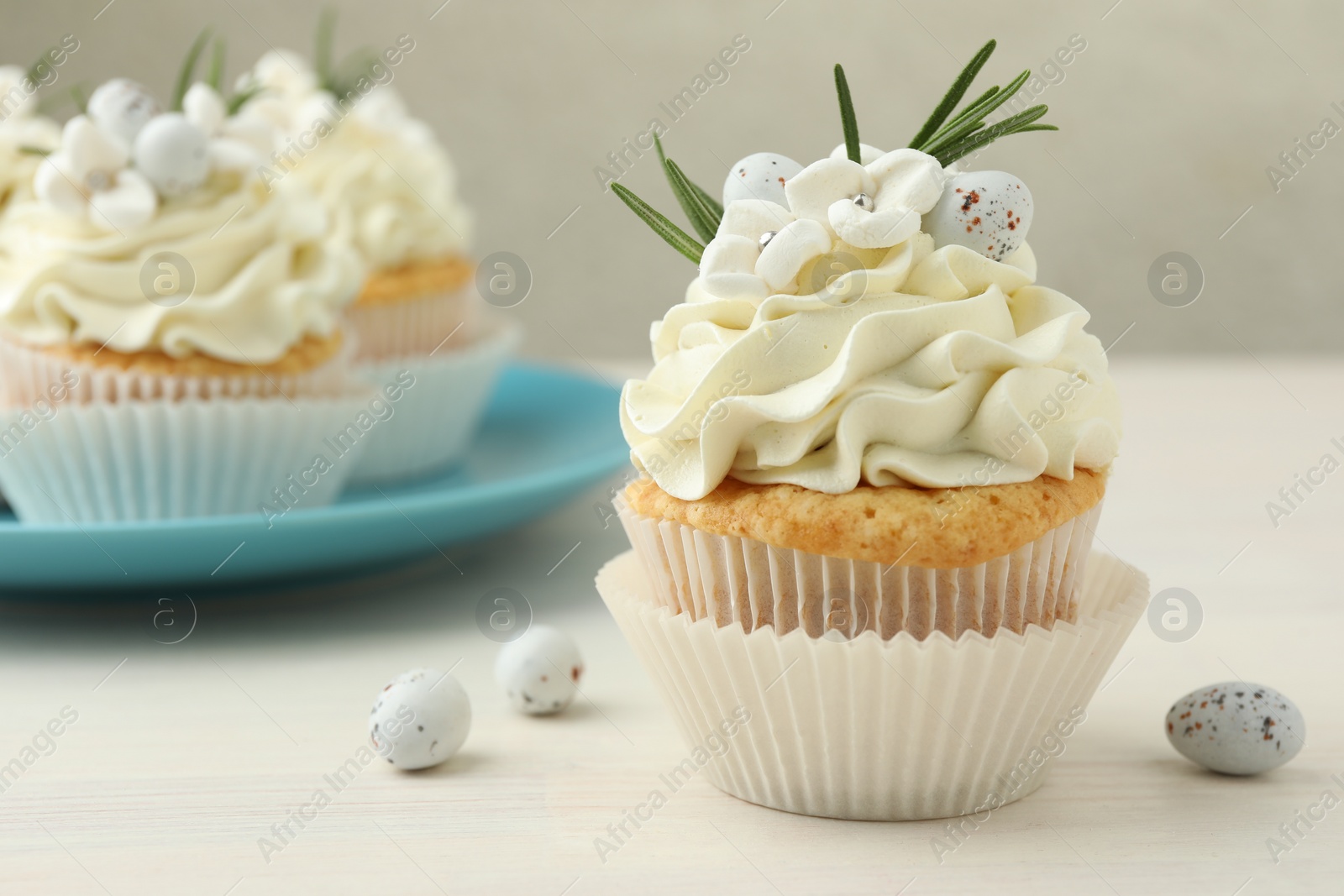 Photo of Tasty Easter cupcakes with vanilla cream on light wooden table