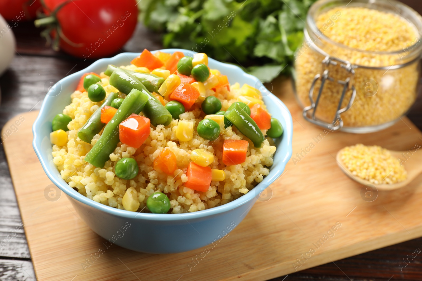 Photo of Tasty millet porridge with vegetables in bowl on wooden table, closeup