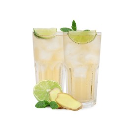 Glasses of tasty ginger ale with ice cubes and ingredients isolated on white
