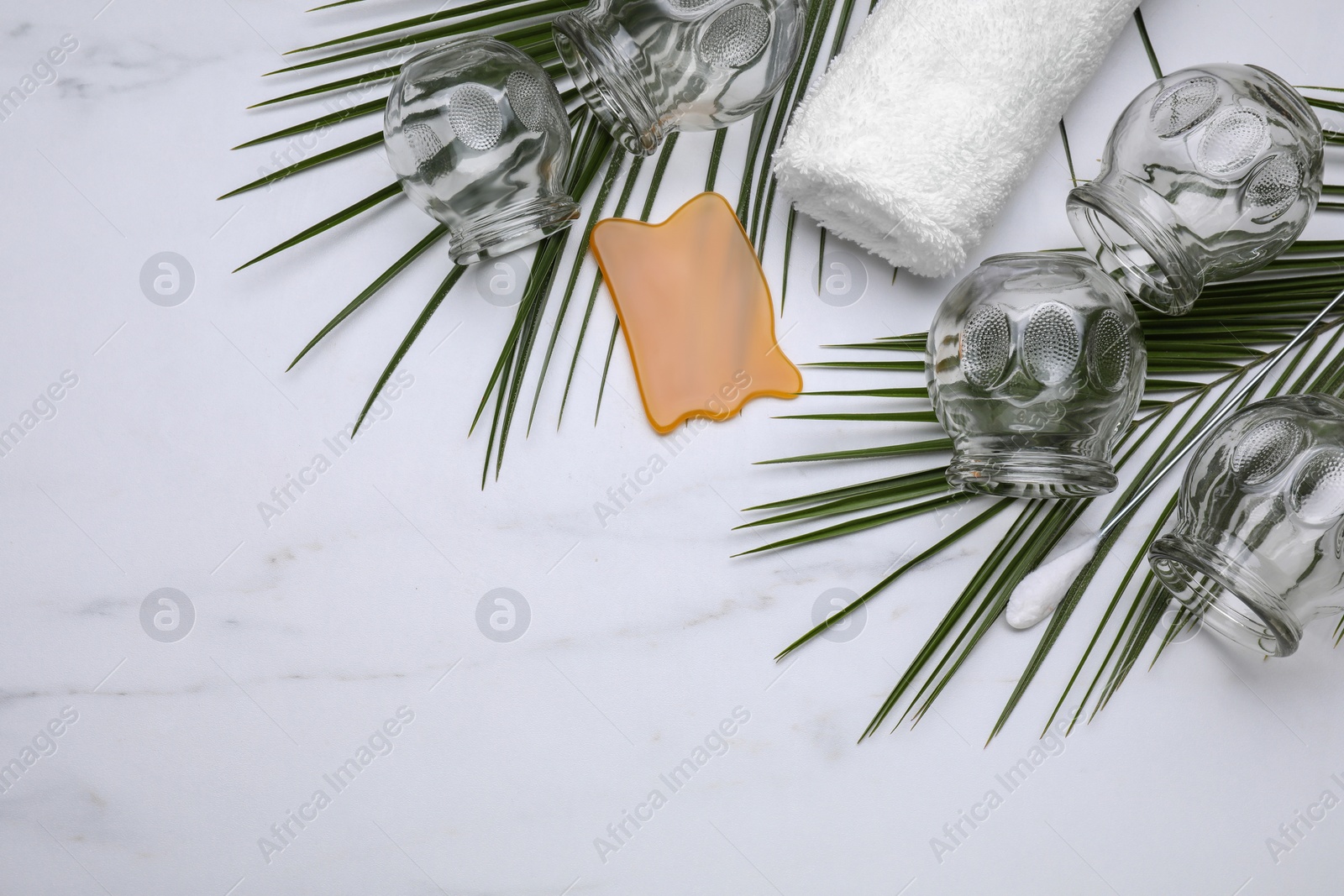 Photo of Cupping set, gua sha and green leaves on white table, flat lay. Space for text