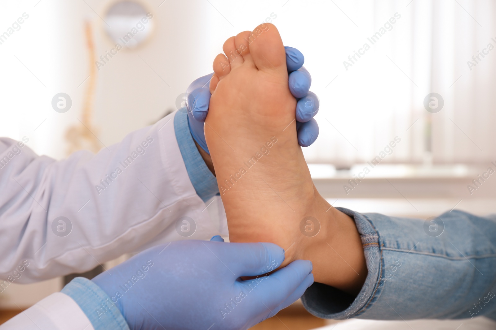 Photo of Male orthopedist checking patient's foot in clinic, closeup
