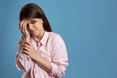 Photo of Young woman suffering from migraine on light blue background. Space for text